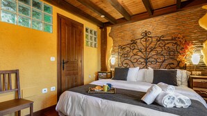 A hotel room with a wooden bed, a brick wall, and a decorative metal headboard. - Country House 'El Llosín' with Private Terrace, Balcony and Wi-Fi (Ribadesella)