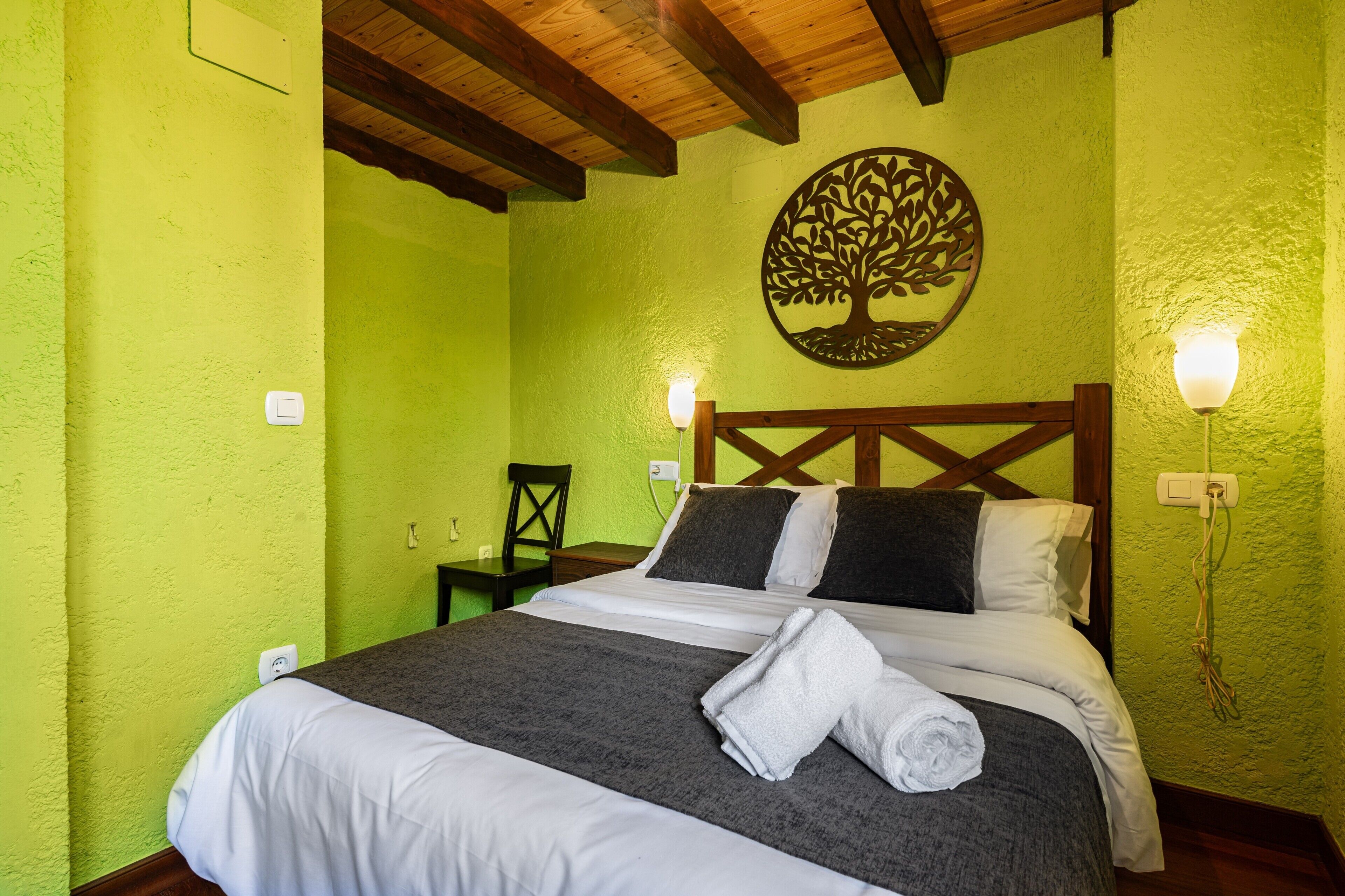 A room with a bed, a chair, and a wall-mounted light fixture.