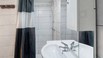 A bathroom with a white sink, a mirror, and a shower curtain.