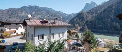 Ein Hotel mit Blick auf Berge, mit weißer Fassade, Metallbedachung und Blick auf einen See und die Berge.