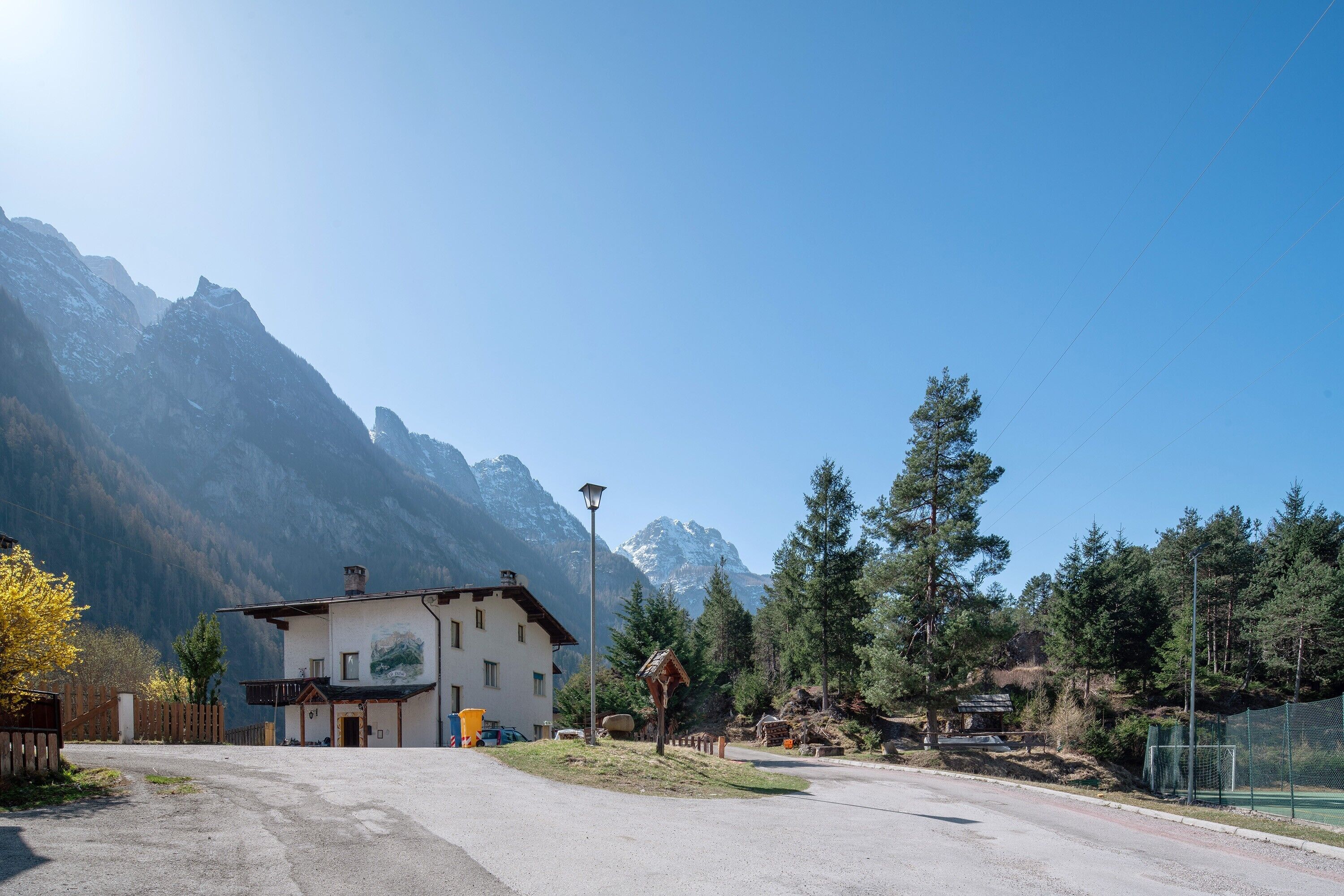 Un chalet de montagne doté d’un grand bâtiment, d’une allée pavée et offrant une vue sur les montagnes environnantes.