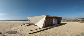 Ein Gebäude am Strand mit geneigtem Dach, einer Holzterrasse und einem Schild, das einen Pferdverleih anzeigt.
