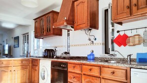 A kitchen with wooden cabinets, a washing machine, a coffee maker, and a dishwasher.