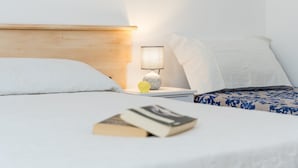 Una cama bien hecha con un libro y una lámpara sobre una mesita de noche.