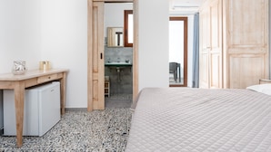 Une chambre comprenant un lit, un bureau, un petit réfrigérateur, une salle de bain avec un lavabo et un miroir, et une armoire.