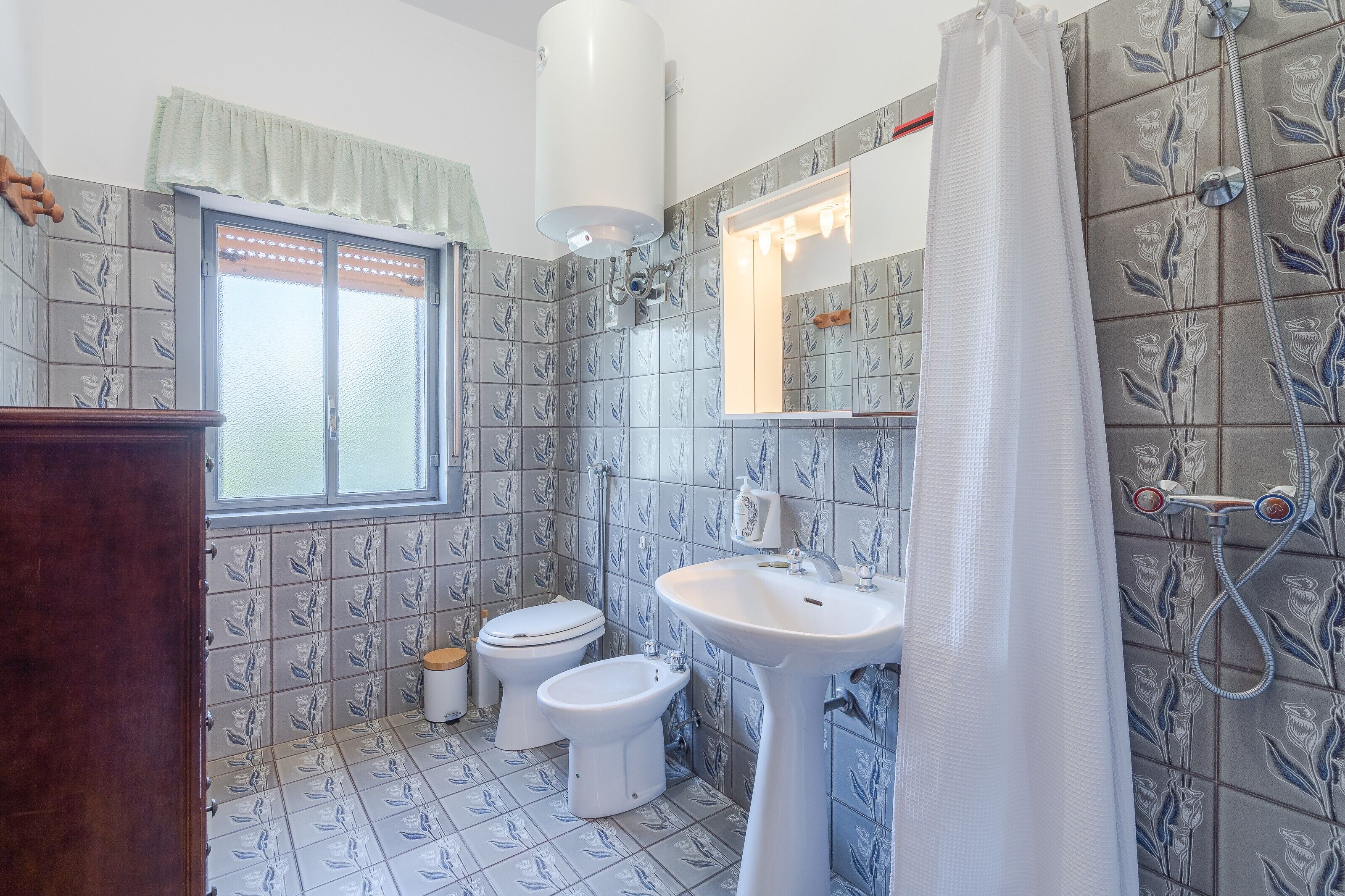 Un baño con inodoro, bidé, lavabo y ducha.