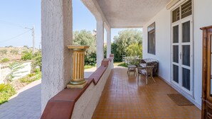 A covered outdoor area with a tiled floor, a column, a table with chairs, and a door. - Country House 'Casa Susanna' with Mountain View, Wi-Fi and Air Conditioning (avola)