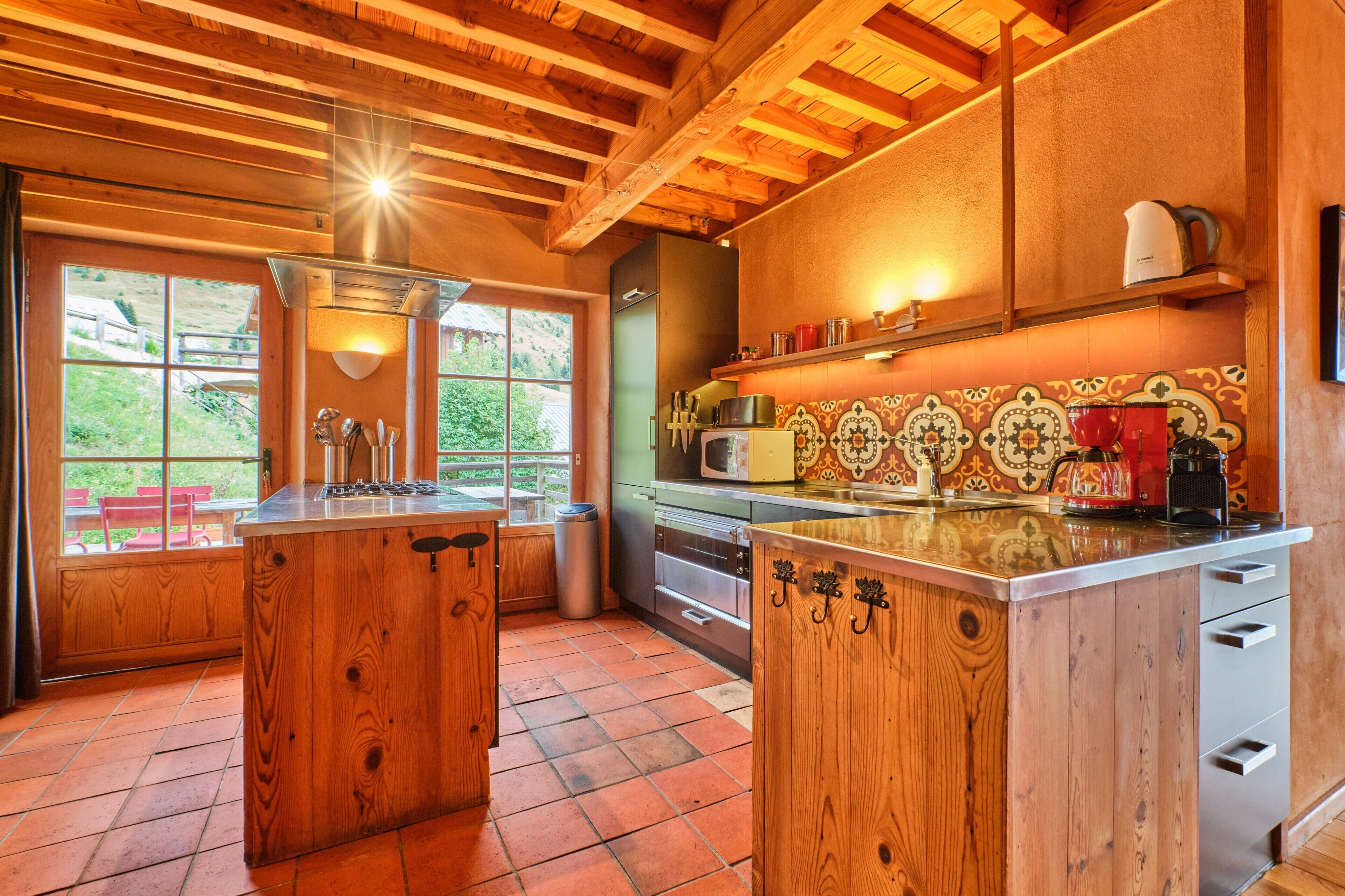 Une cuisine avec des meubles en bois, un îlot central, un four à micro-ondes et une vue sur l’extérieur.