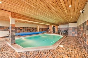 An indoor swimming pool with a wooden ceiling, tiled walls, and a blue bench. - Apartment 'La Forêt' with Mountain View, Balcony and Wi-Fi (Villard-Reculas)