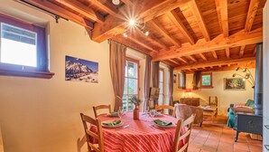 Un coin repas avec une nappe rouge, des chaises en bois, un lustre et un plafond en bois rustique.
