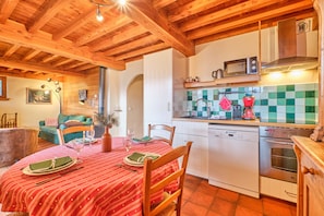 A cozy kitchen with wooden beams, a dining table set for two, a microwave, and a dishwasher. - Apartment 'La Forêt' with Mountain View, Balcony and Wi-Fi (Villard-Reculas)