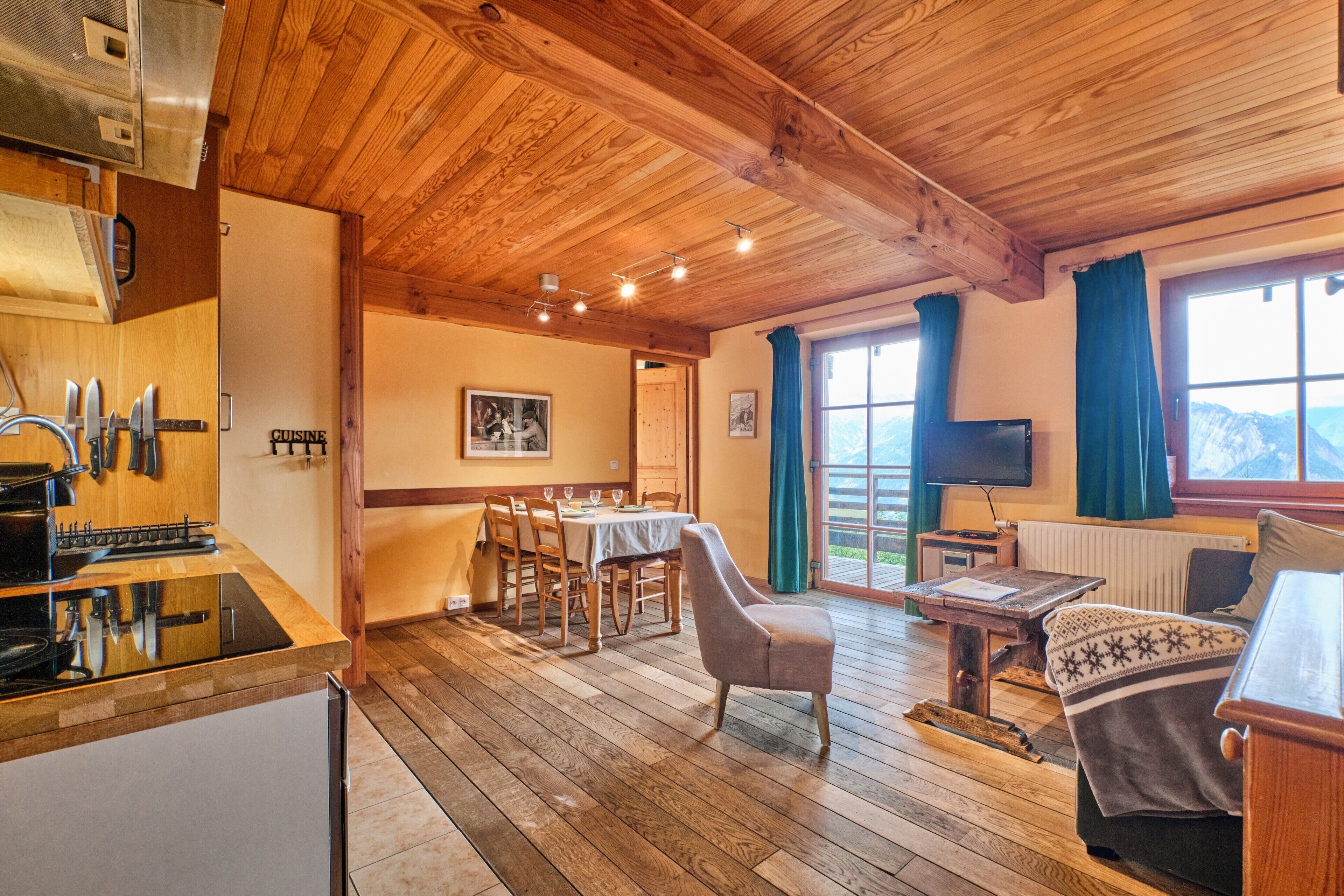Ambiente in legno con zona pranzo, angolo cottura e area salotto.