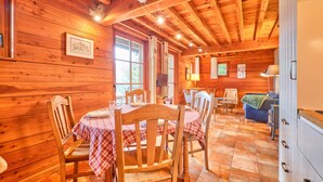 Ein Holzblockhaus mit Essbereich, einer Couch und einer Küche.