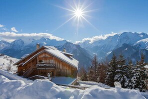 A wooden chalet with a balcony, surrounded by snow-covered mountains and a clear sky. - Apartment 'Les Vallons' with Mountain View, Private Terrace and Wi-Fi (Villard-Reculas)