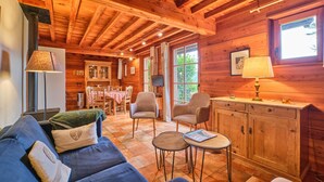 A wooden cabin interior with a sofa, chairs, a dining table, and a cabinet. - Chalet 'Il Fera Beau Demain' with Mountain View, Private Terrace and Wi-Fi (Villard-Reculas)