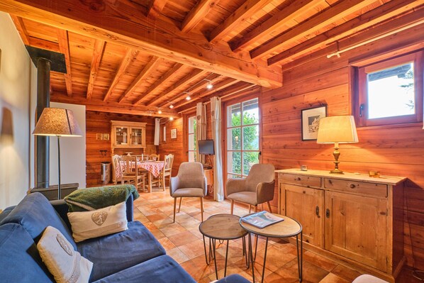 A wooden cabin interior with a sofa, chairs, a dining table, and a cabinet. - Chalet 'Il Fera Beau Demain' with Mountain View, Private Terrace and Wi-Fi (Villard-Reculas)