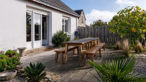 Een huis met een patio, houten tafel en bankjes.