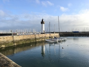 Un port doté d’un phare, de bateaux et d’une marina où sont amarrés de nombreux voiliers.
