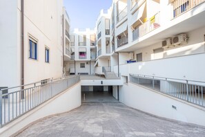 Un immeuble résidentiel à plusieurs étages, doté de balcons, de climatiseurs et d’un escalier central.