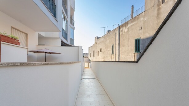 A narrow corridor with a tiled floor, a potted plant, and an umbrella.