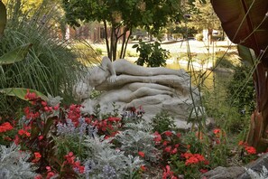 Une sculpture représentant des figures allongées, placée dans un jardin.
