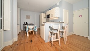 A compact kitchen with white cabinets, a microwave, and a coffee machine. There is a dining table with chairs and a small refrigerator. - Le Clos du Casino, T3 "Le Céciré" for 4 to 6 guests (Bagnères de Luchon)