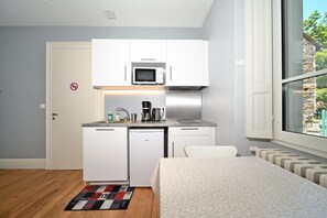 A compact kitchenette with a microwave, coffee maker, and small refrigerator.