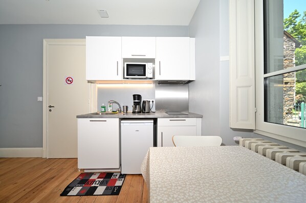 A compact kitchenette with a microwave, coffee maker, and small refrigerator.