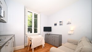 Ein kompakter Wohnraum mit Küchenzeile, Esstisch, Sofa und Bildern an der Wand.