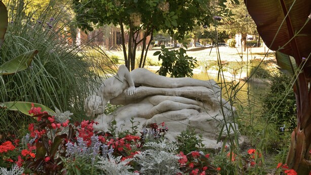 Eine Skulptur von liegenden Figuren in einem Garten.