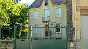 A two-story house with a balcony, a green gate, and a number 14 sign.