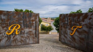 A rustic entrance with rusted metal gates marked with large letters.