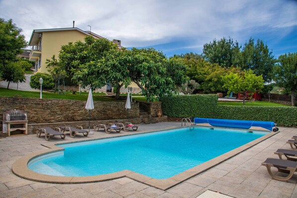 A rectangular swimming pool with a blue liner, surrounded by lounge chairs and umbrellas.