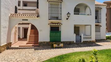 Un edificio de dos pisos con techo de tejas, una puerta verde y una escalera de piedra que conduce a la entrada.