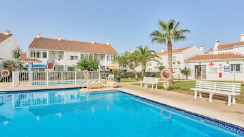 Una piscina con un flotador salvavidas, un banco y una palmera.