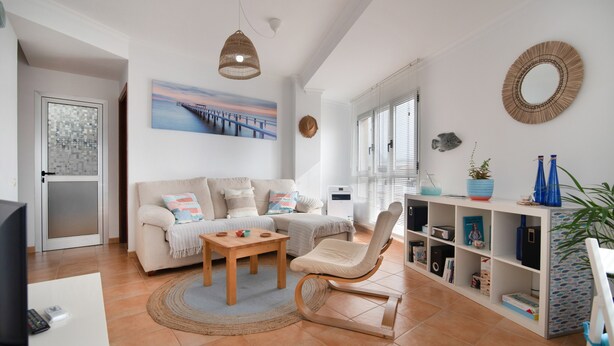 A living room with a sofa, a wooden chair, a coffee table, a TV, and a bookshelf.