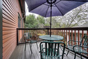 En træterrasse med et bord, stole, en parasol og et gelænder.