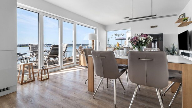 Et moderne køkken med spiseplads, store vinduer og udsigt til vandet.