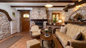 A cozy living room with a stone fireplace, wooden beams, a sofa, armchairs, and a coffee table. - Vacation home Gianni by Interhome (Labin)