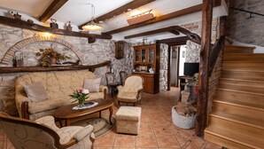 A cozy living room with a stone fireplace, wooden beams, and a staircase. - Vacation home Gianni by Interhome (Labin)