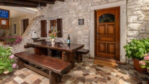 A rustic stone building with a wooden door, a bench, a table, and a welcome mat. - Vacation home Gianni by Interhome (Labin)