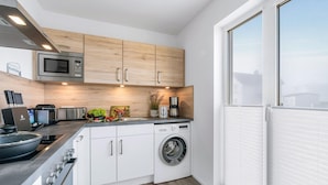 A compact kitchen with a microwave, toaster, sink, and washing machine.