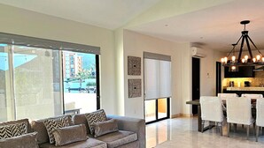 A modern living room with a sofa and a dining area with chairs and a table. - CCV Quivira- 3BR Cozy Home w/ Golf and Restaurants access! (Cabo San Lucas)