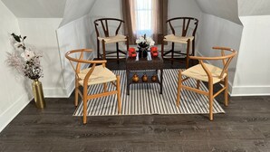 A room with a sloped ceiling, four wooden chairs with woven seats, a small table with decorative items, and a vase with flowers. -  Leave Worries Behind (Wilkes-Barre)