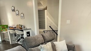A gray sectional sofa with multiple cushions, a power cord, and a woven rug. -  Leave Worries Behind (Wilkes-Barre)