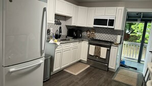 A modern kitchen with white cabinets, a stainless steel refrigerator, a microwave, and a gas stove. -  Leave Worries Behind (Wilkes-Barre)