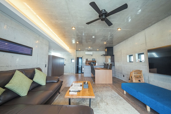 A modern living room with a sofa, coffee table, and a blue bed.