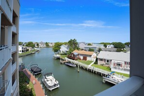 A canal view with boats docked, a house with a dock, and a building with a balcony.