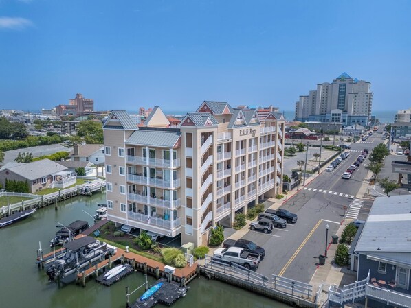 A multi-story hotel with balconies, located near a marina with boats docked.