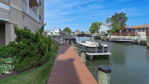 A canal with boats docked, a wooden walkway, and residential buildings.